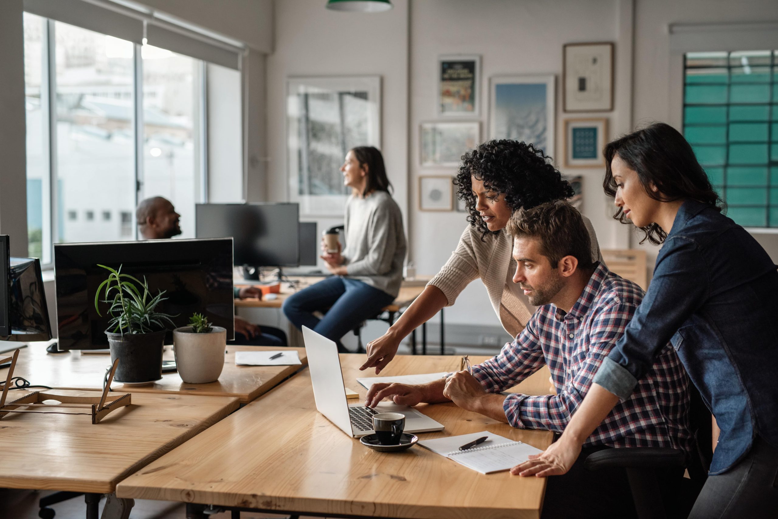 Three young office workers using a laptop together at work